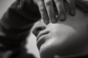 Close-up of a person's face with hand covering eye